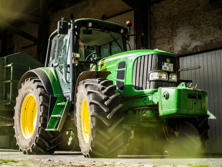 A green tractor parked inside an agricultural equipment building.