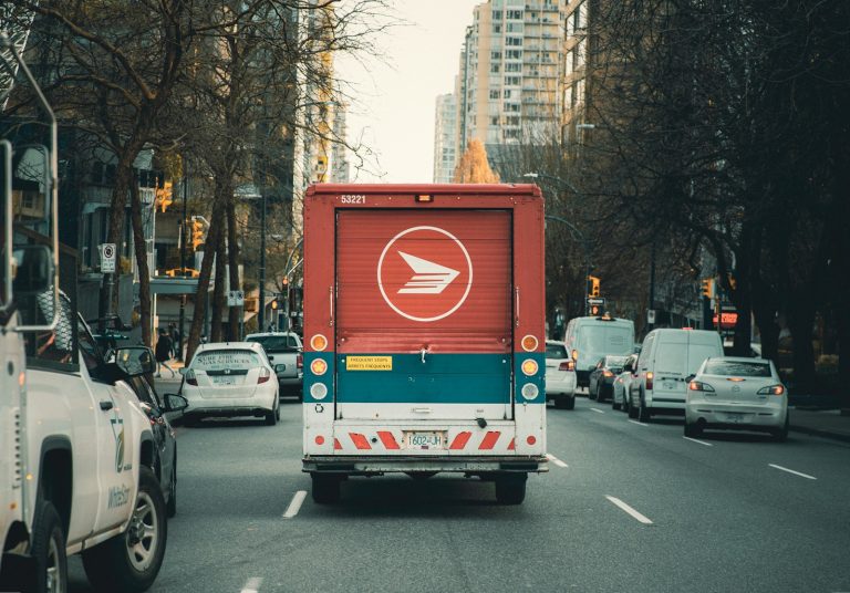 A Canada Post delivery truck travelling on a city street.