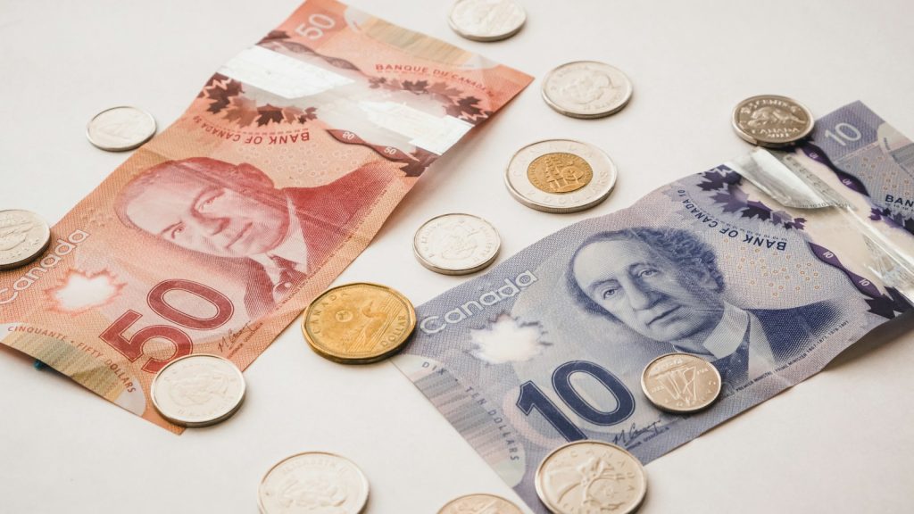 Canadian banknotes and coins arranged on a light surface.