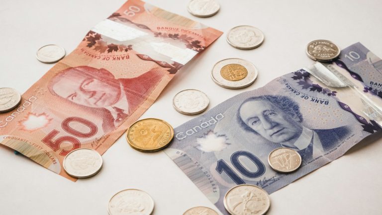 Canadian banknotes and coins arranged on a light surface.