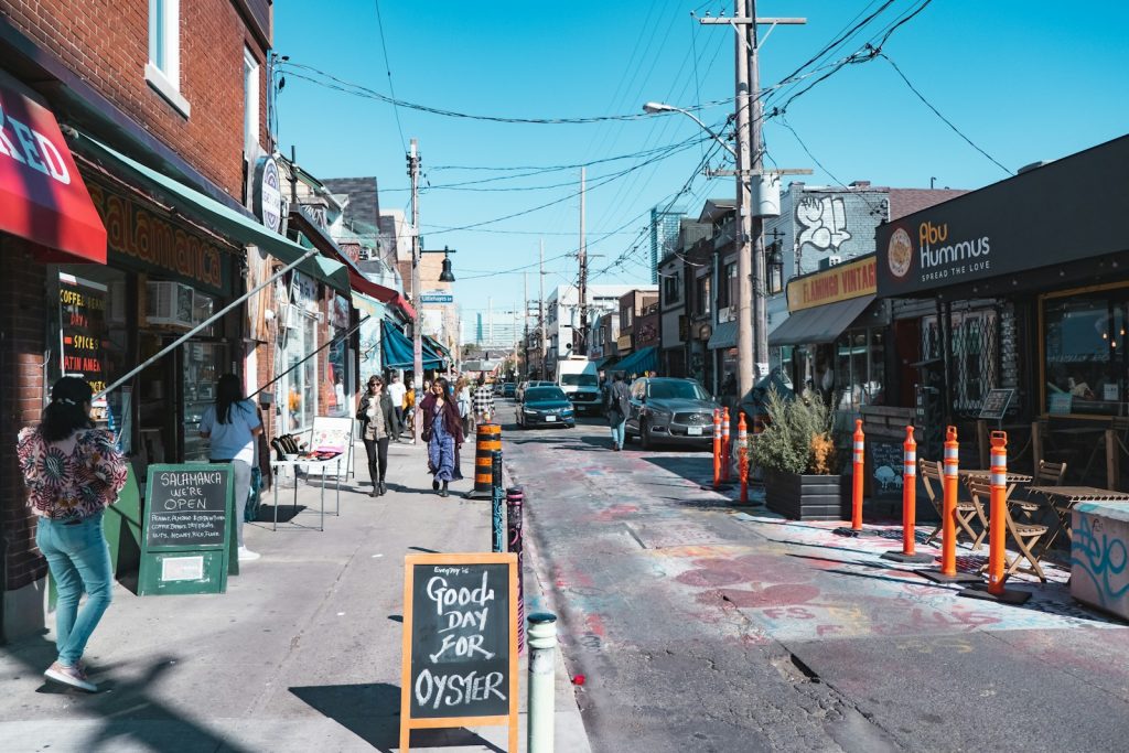 People walking along a busy commercial main street with shops on both sides