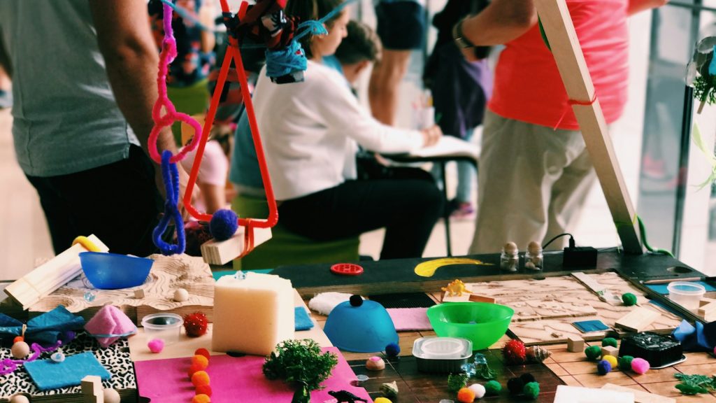 Colourful craft materials cover a table during a community art workshop.