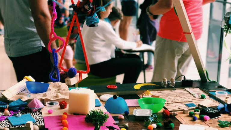 Colourful craft materials cover a table during a community art workshop.