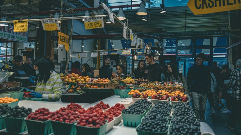 Produce market with price signs and shoppers — illustrative