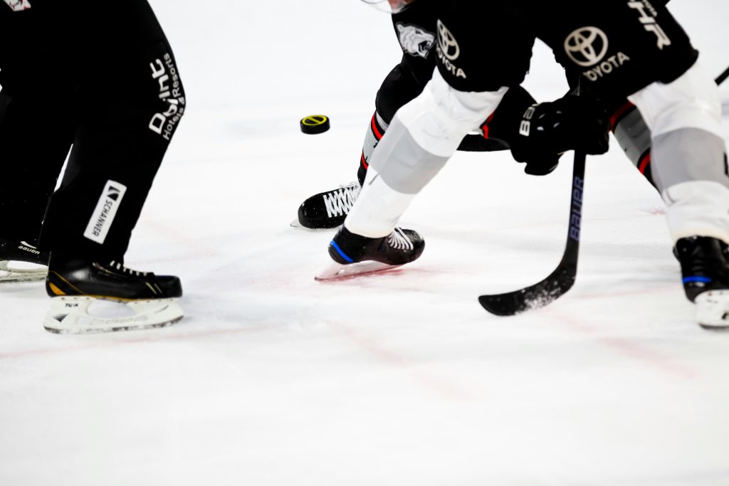 Ice hockey players’ skates and sticks around a puck on the ice