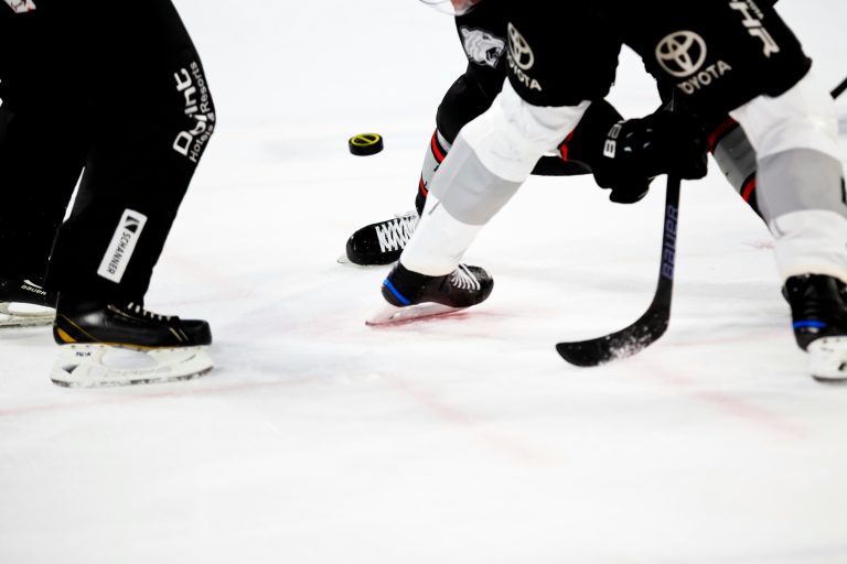 Ice hockey players’ skates and sticks around a puck on the ice