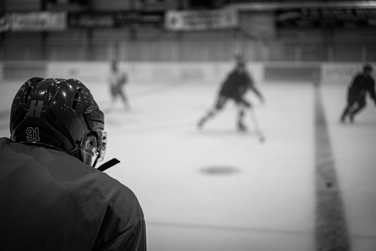 Ice-hockey player watching teammates practise on an indoor rink