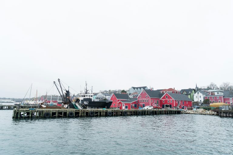 Fishing boat and colourful waterfront buildings in an Atlantic Canadian harbour, illustrative stock image.