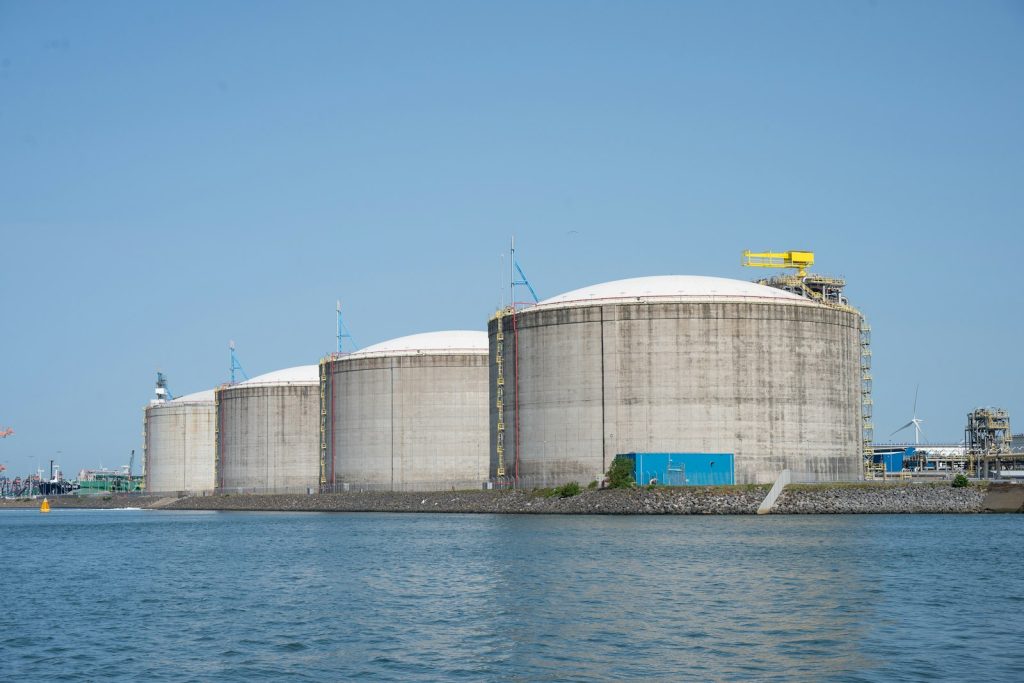 Large industrial storage tanks beside a body of water