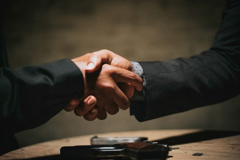 Two people shaking hands across a table, illustrative stock image.