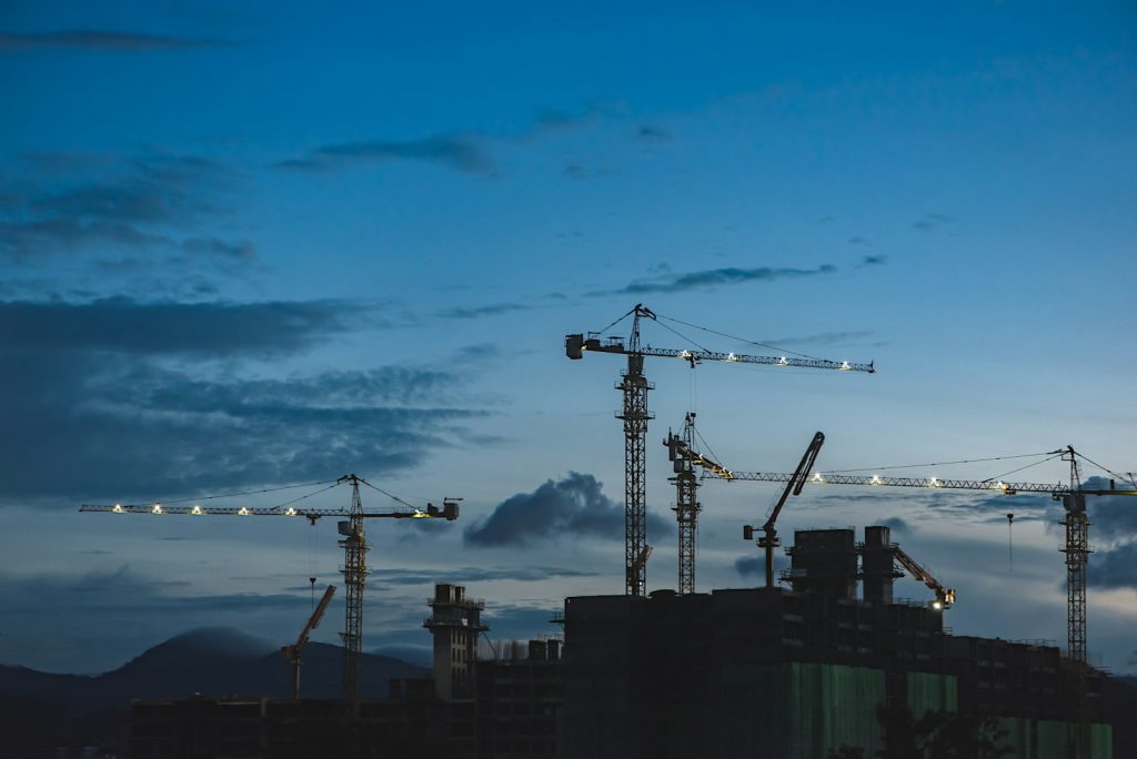 Construction cranes working above a building site at dusk