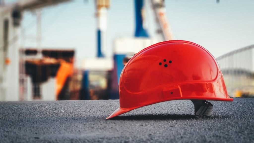 Illustrative red construction hard hat at a work site
