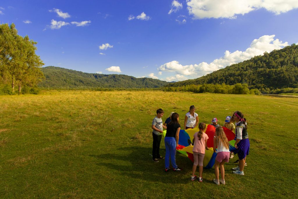 Illustrative group of children and adults doing an outdoor camp activity