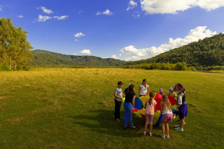 Illustrative group of children and adults doing an outdoor camp activity
