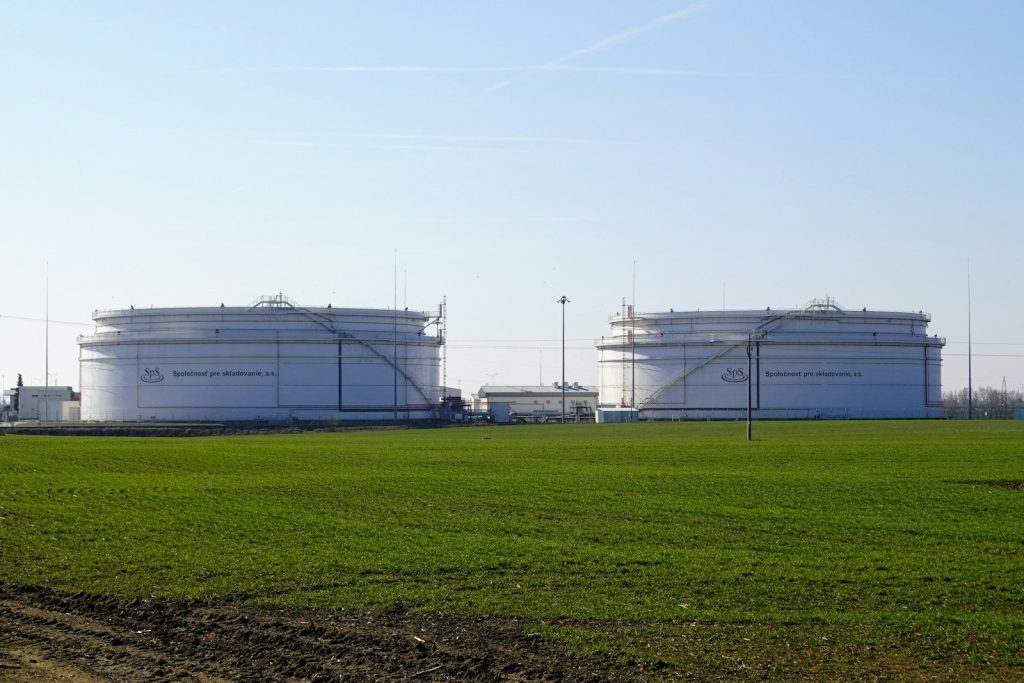 Two large petroleum storage tanks behind a green field
