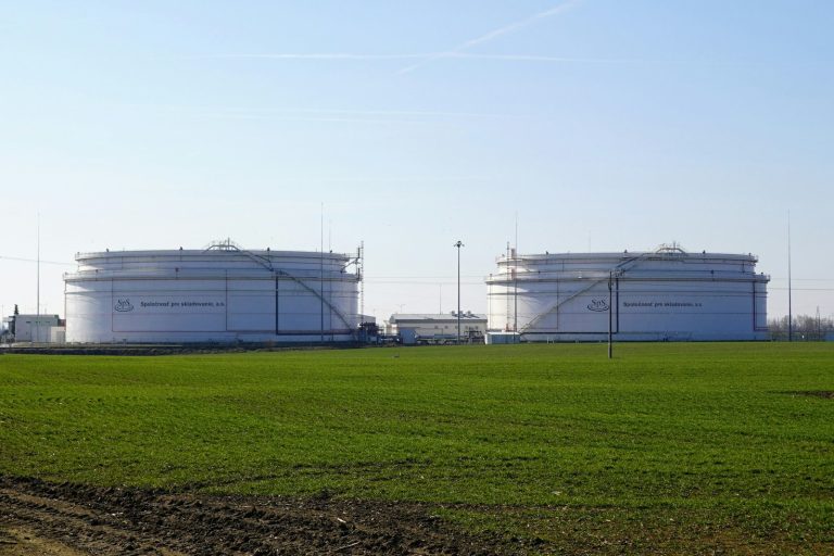 Two large petroleum storage tanks behind a green field