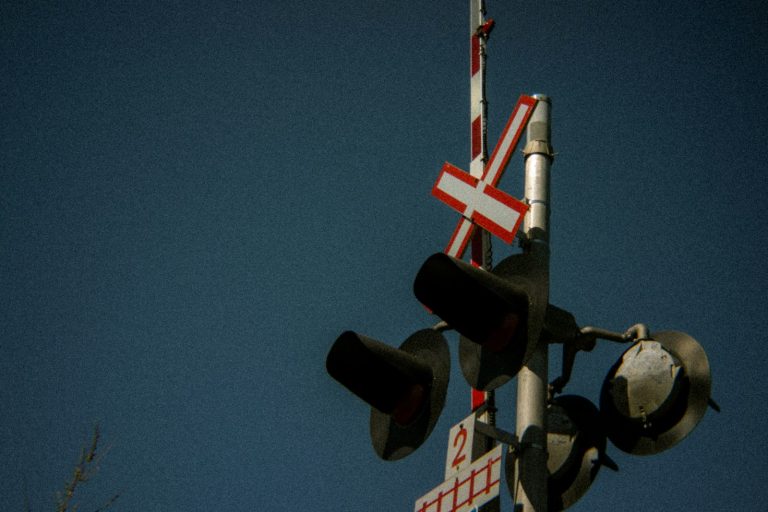 Railway crossing warning signal against a clear blue sky, illustrative stock image