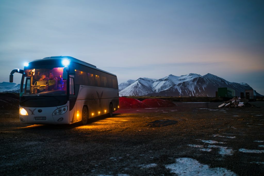 Illustrative coach bus in a mountainous rural landscape at dusk