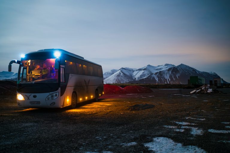 Illustrative coach bus in a mountainous rural landscape at dusk