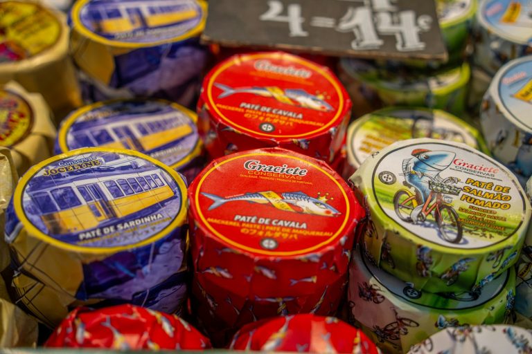Round tins of smoked fish products displayed on a market shelf
