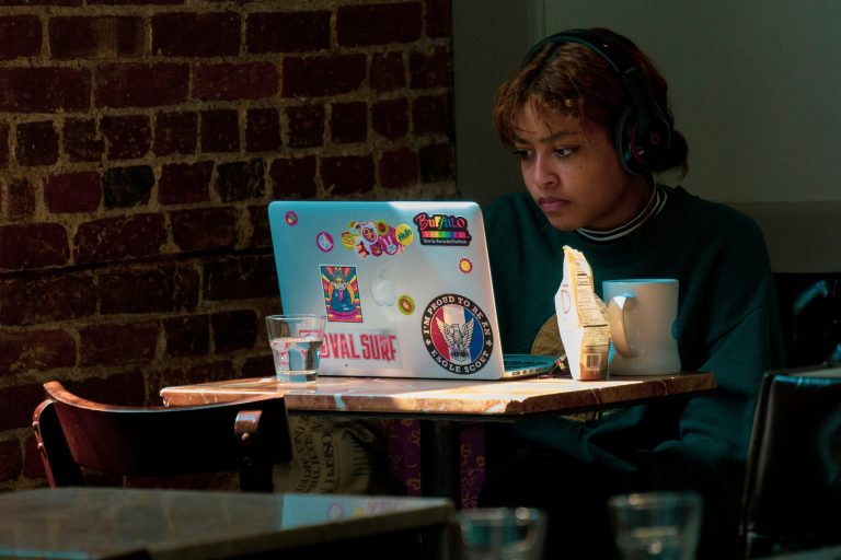 Young person wearing headphones working on a laptop, illustrative stock image.
