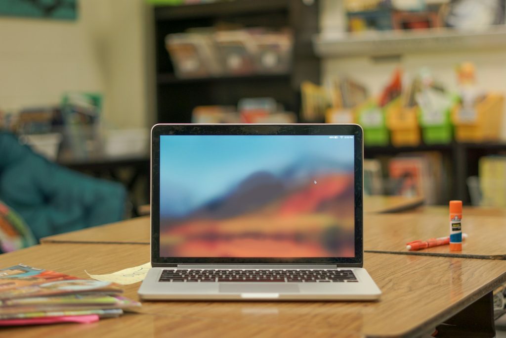A laptop computer on a desk in a classroom.