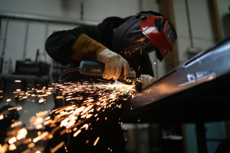Worker grinding a metal beam as sparks fly