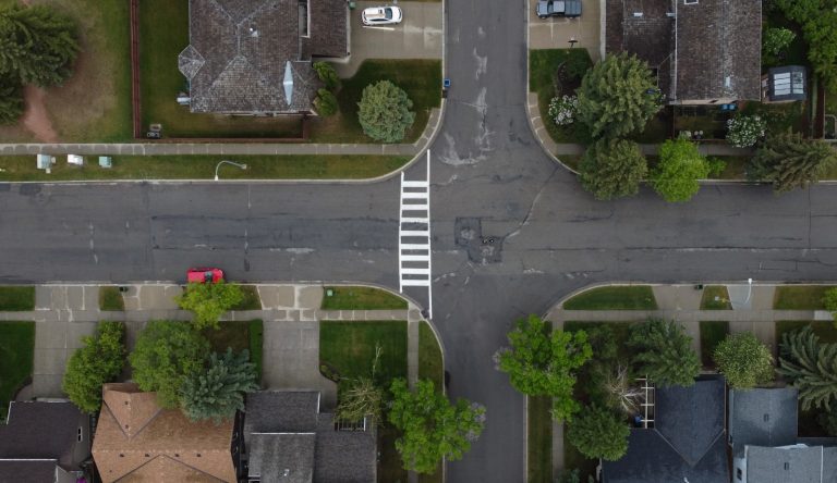 A marked pedestrian crosswalk at a residential intersection seen from above.