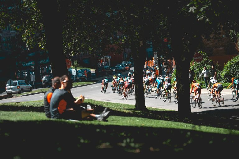 A road-cycling peloton racing along a city street.