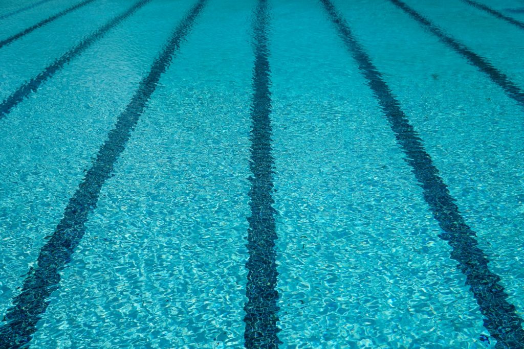 Lane markings beneath clear swimming-pool water — illustrative