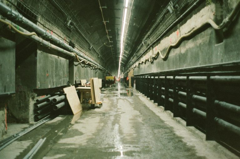 Long underground concrete tunnel with pipes and electrical lines