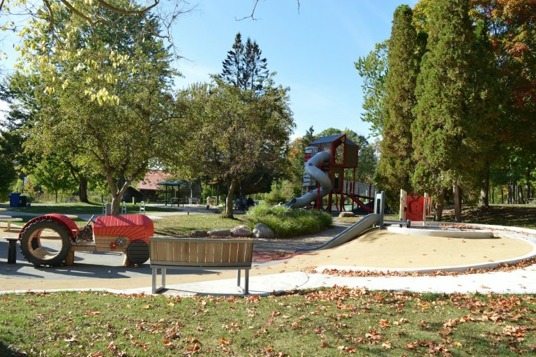 An accessible playground surrounded by trees in an urban park.