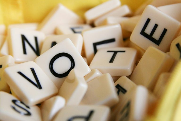 Letter tiles spelling VOTE among scattered cream-coloured tiles