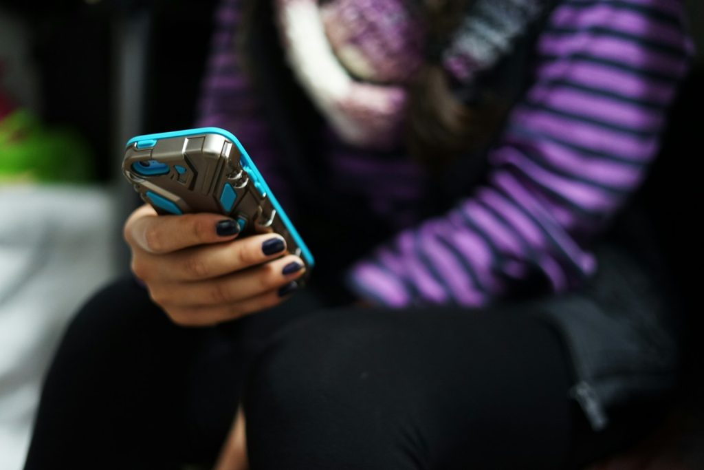 A young person holding and using a smartphone.