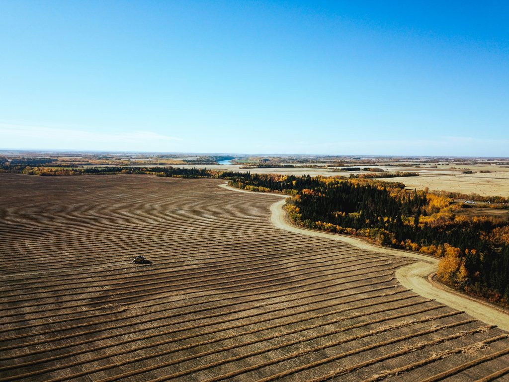 Wide view of harvested fields and autumn trees in Canada