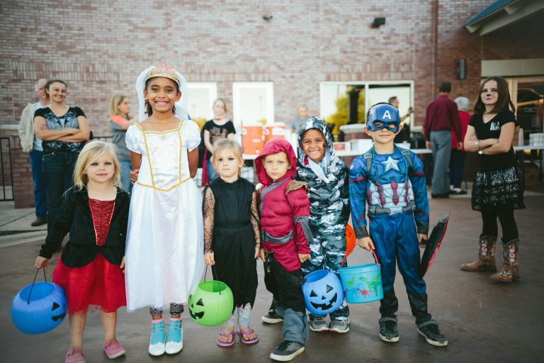 A group of children wearing Halloween costumes and carrying treat buckets