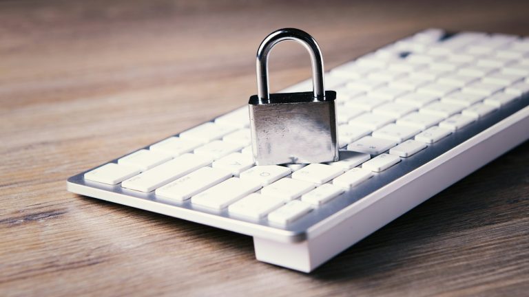 Open metal padlock resting on a computer keyboard