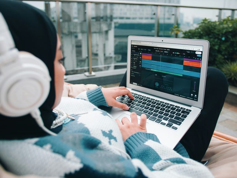 A person wearing headphones arranging music on a laptop