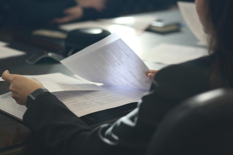 Person reviewing printed documents at a desk, illustrating proposed federal regulatory changes
