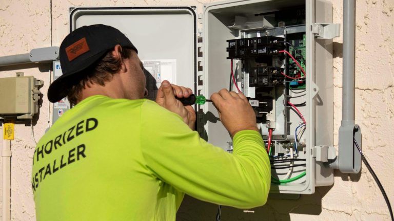 Electrician using a screwdriver on an outdoor electrical panel