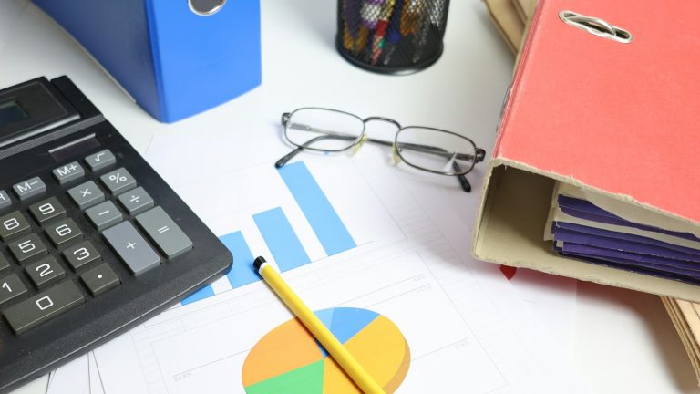 Calculator, charts, folders and glasses on a desk, illustrative financial data image