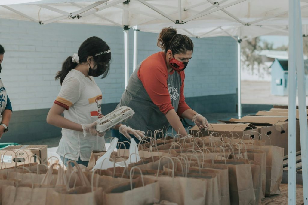 Volunteers packing groceries into paper bags at a community food distribution