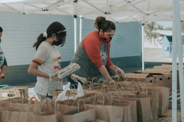 Volunteers packing groceries into paper bags at a community food distribution