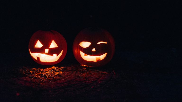 Two illuminated carved pumpkins at night, illustrative Halloween image