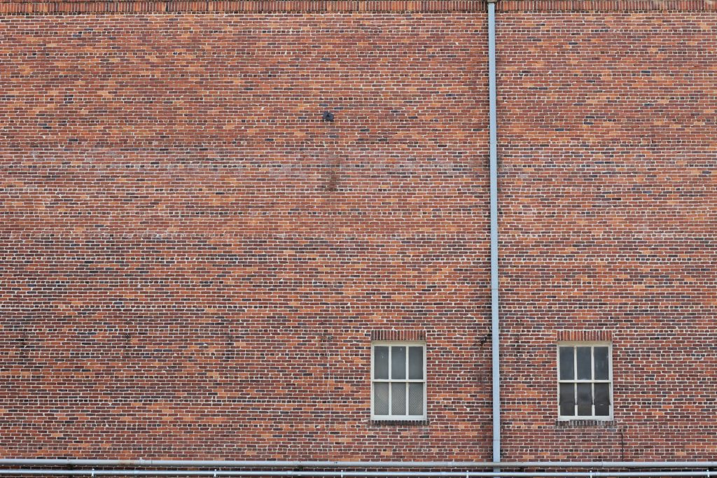 Weathered brickwork and two windows on an old building
