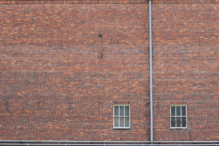 Weathered brickwork and two windows on an old building