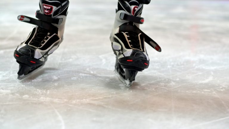 Pair of hockey skates resting on a bench beside an ice rink