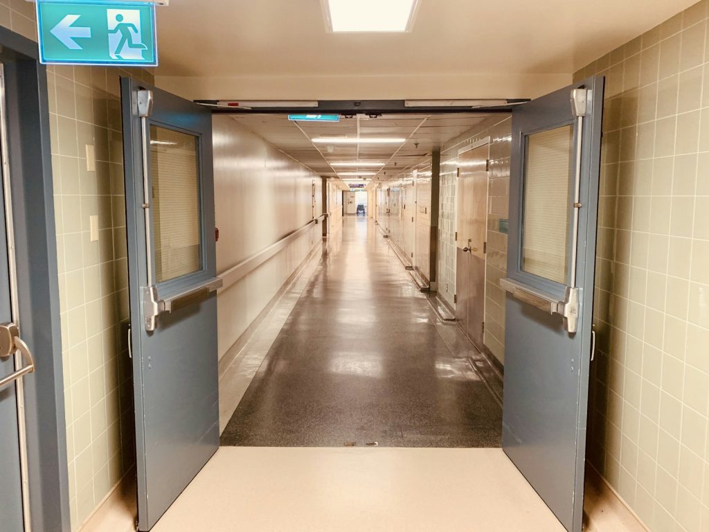 Empty hospital corridor with open doors, illustrative stock image.