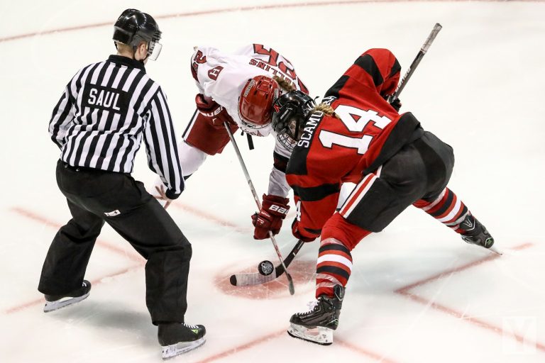 Ice hockey players taking a faceoff on an indoor rink