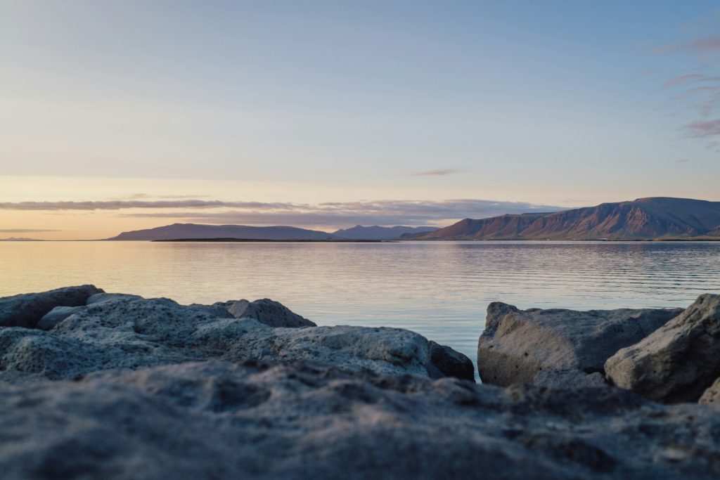 Calm Icelandic bay and volcanic rocks at low sun, illustrating Arctic talks in Reykjavík